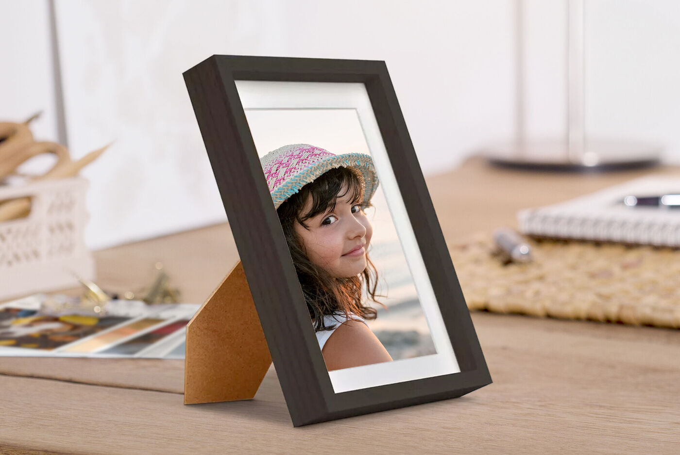 Tirage photo encadré posé sur un bureau montrant une petite fille avec un chapeau