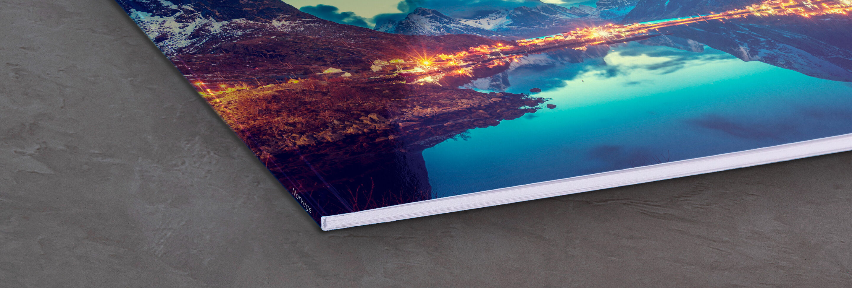 Gros plan d'un livre photo CEWE avec page de paysages.