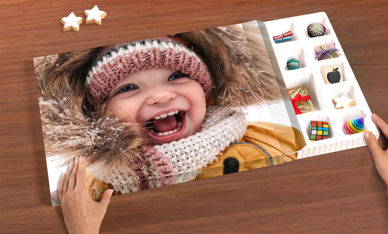 Un album photo ouvert avec des souvenirs personnels. Les mains de quelqu'un tiennent le livre sur une table en bois.