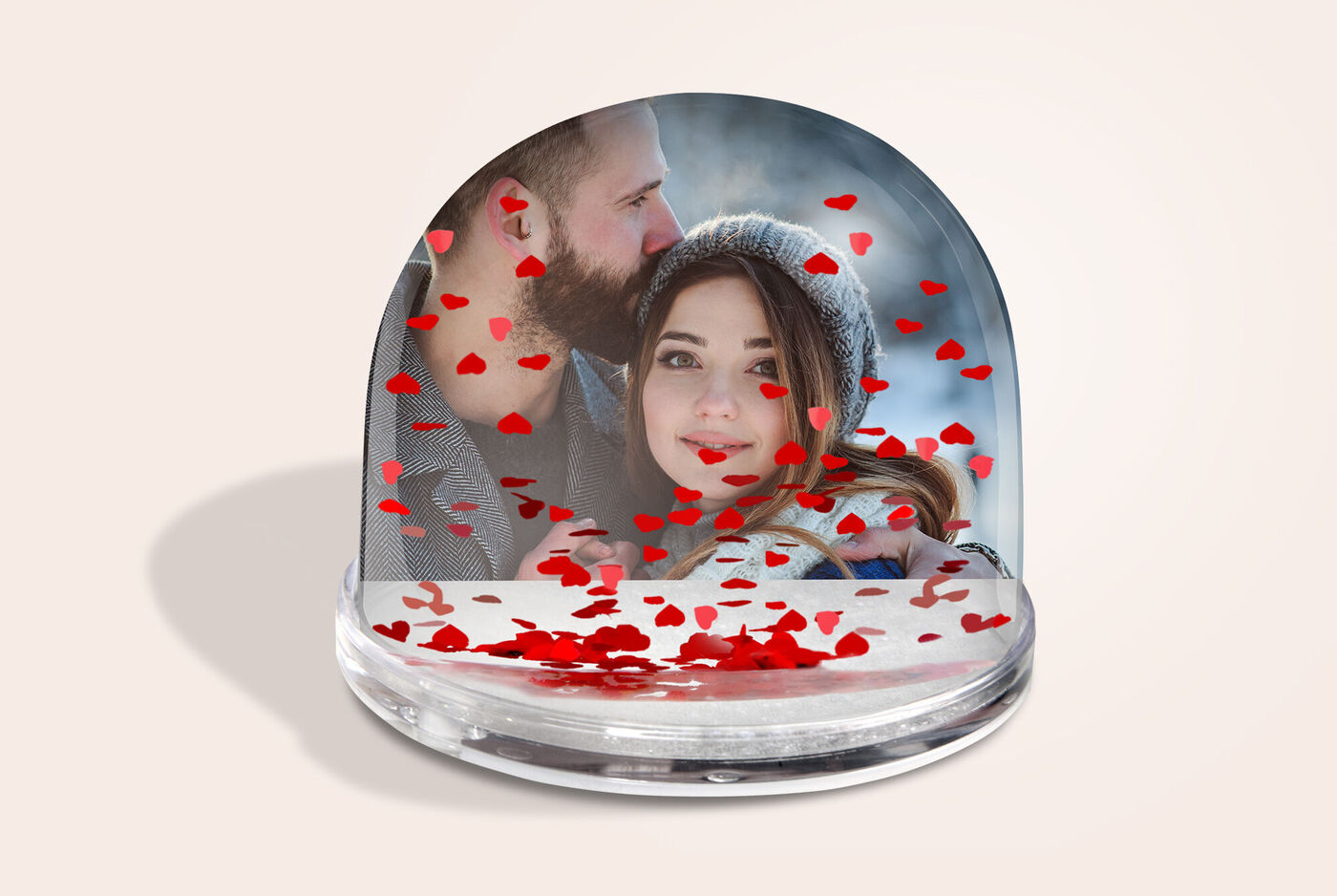 Personnes dans une boule à neige entourées de cœurs rouges