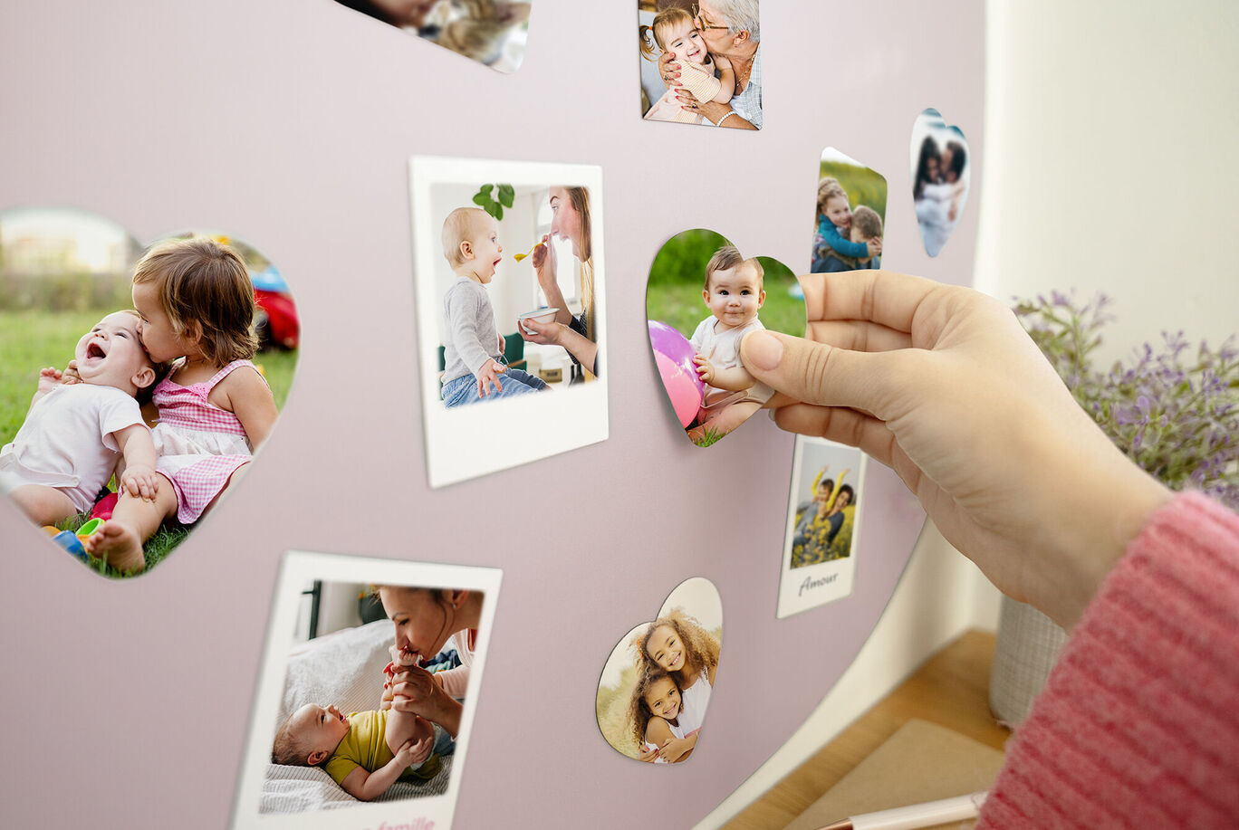 Une personne suspend des photos en forme de cœur sur un mur avec de la lavande.
