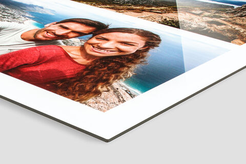 Couple amoureux tenant un album photo CEWE avec des souvenirs de vacances