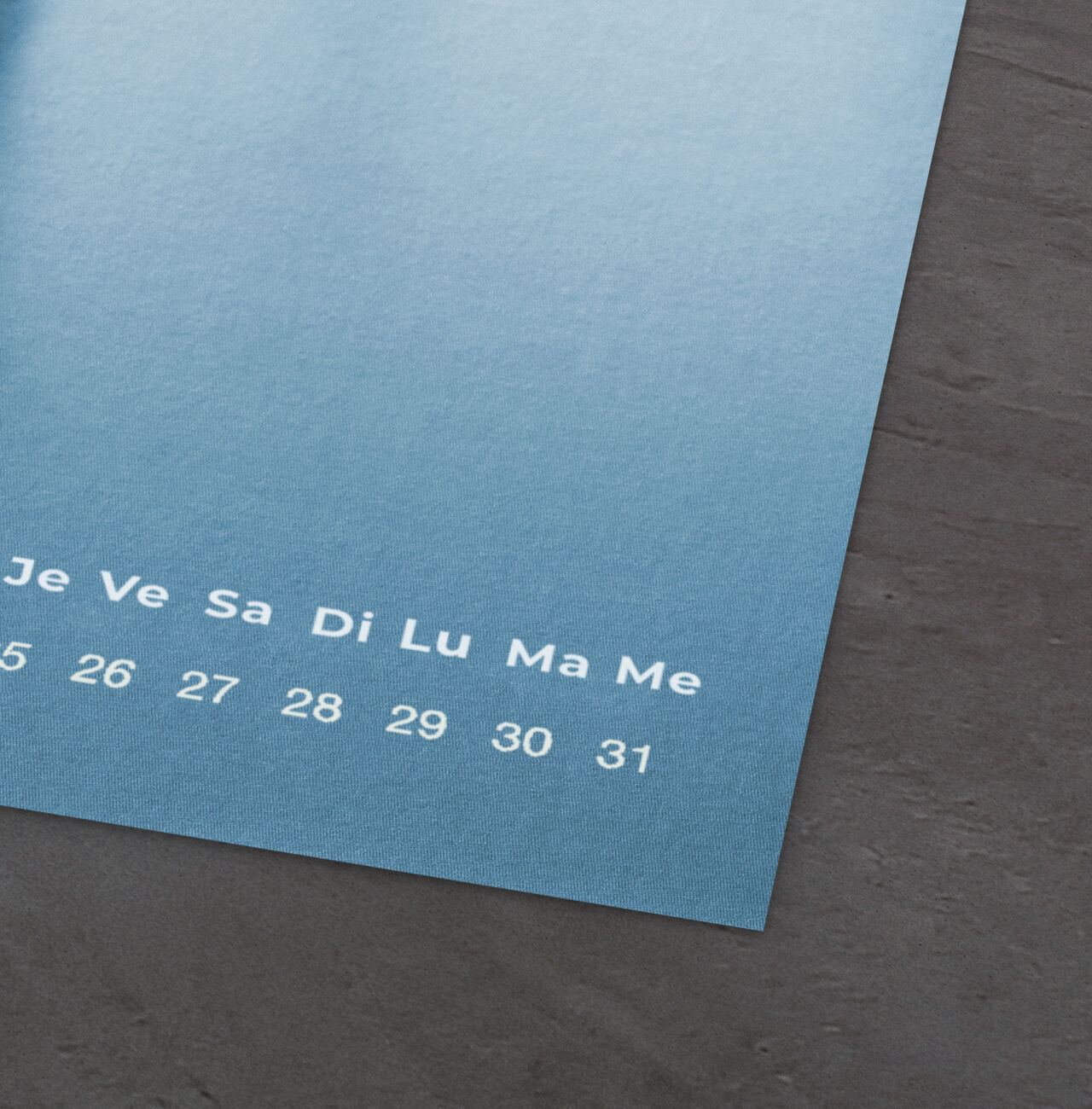 Un calendrier mural coloré avec des nuances de bleu et des dates. Le début de la semaine est indiqué.