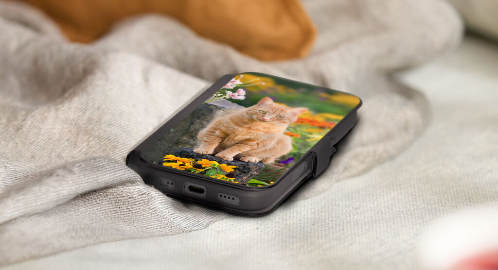 Coque noire personnalisée avec un chat, posée sur une couverture