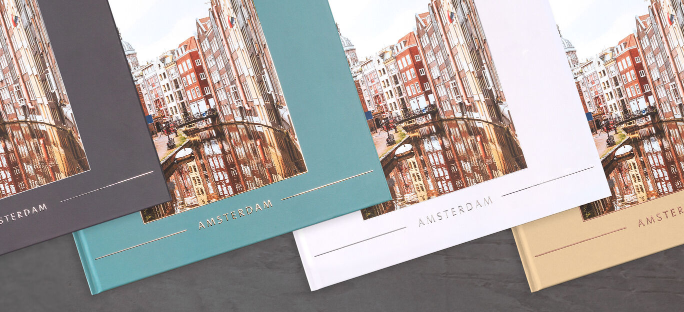 Trois livres photo CEWE sur Amsterdam de différentes couleurs sont posés sur une table.
