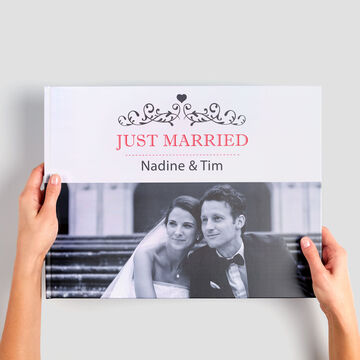 Un couple de mariés présente un livre photo avec leur nom.