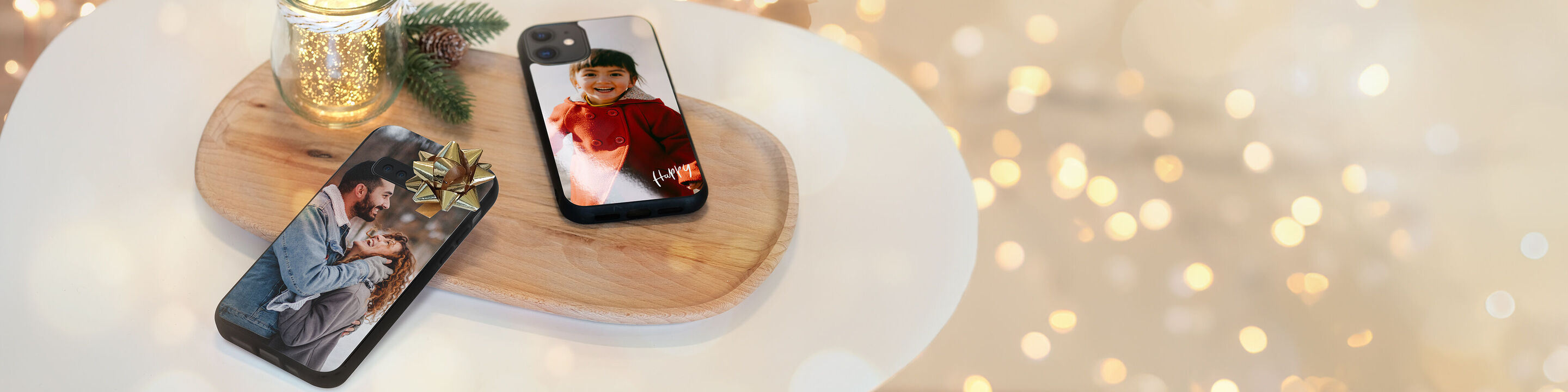 Deux smartphones avec des coques personnalisées sur une planche en bois, entourés de décorations de Noël.