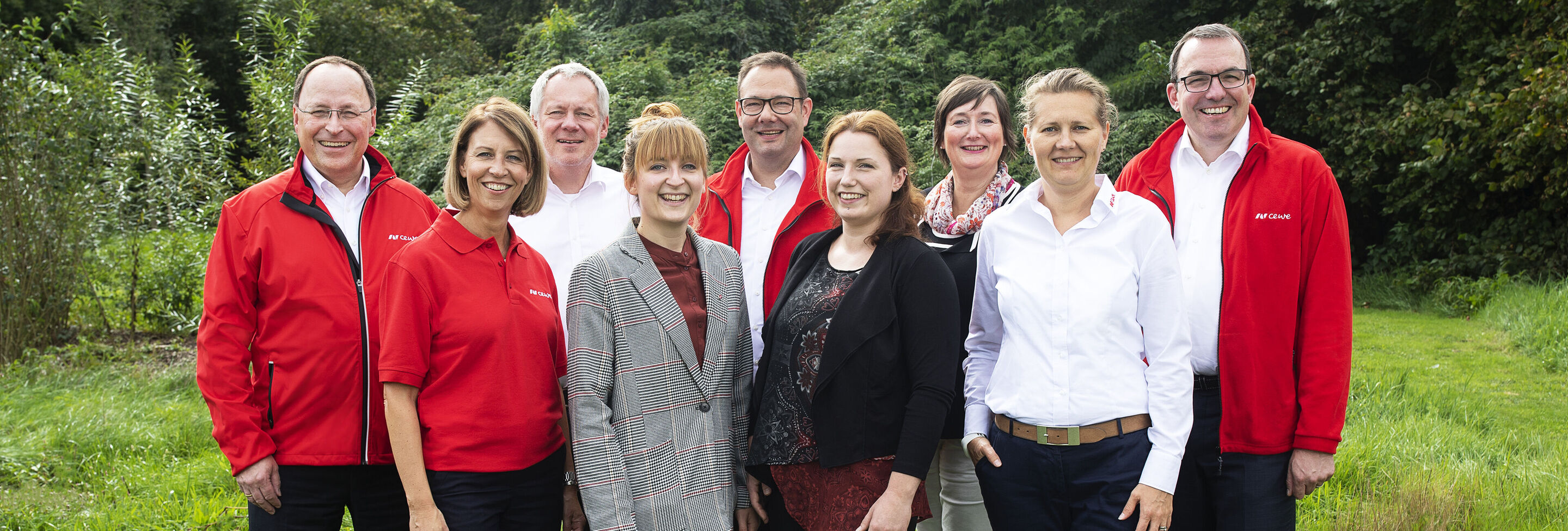 Groupe de personnes à l'extérieur avec des sourires accueillants, habillées en rouge et blanc