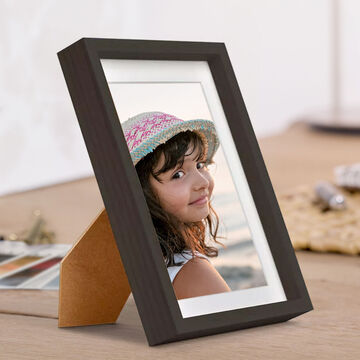 Un cadre photo marron sur une table avec une photo d'une personne portant un chapeau de soleil.