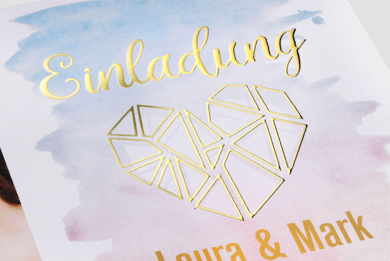 Invitation avec un design en cœur doré sur fond pastel.