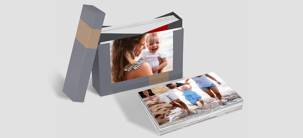 Un album CEWE affectueusement conçu est sur une table. Il montre des moments heureux de vacances. Sur la couverture, une mère et son bébé dans l'eau. À côté, un livre ouvert avec d'autres photos.