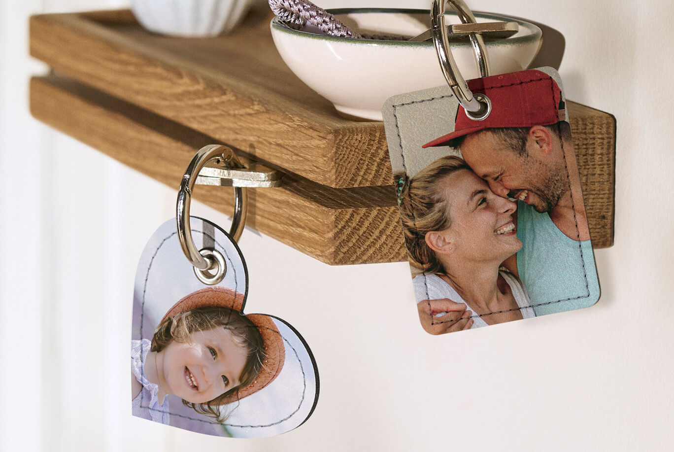 Deux porte-clés individuels avec des photos personnelles pendent d'une étagère en bois. Le porte-clés en forme de cœur montre une belle image.