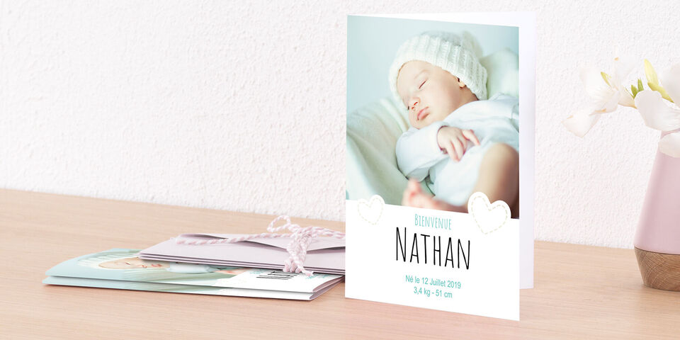Un design de carte de naissance affectueux pour Nathan, placé sur une table.