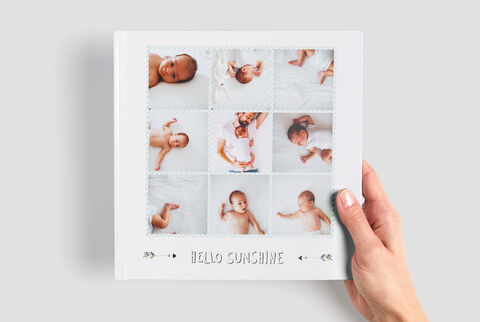 Une personne tient un album photo CEWE avec des photos de bébés apaisantes. Chaque page montre des moments différents du bébé.
