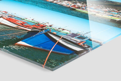 Des bateaux colorés reposent dans une eau claire, avec le soleil et un ciel bleu en arrière-plan