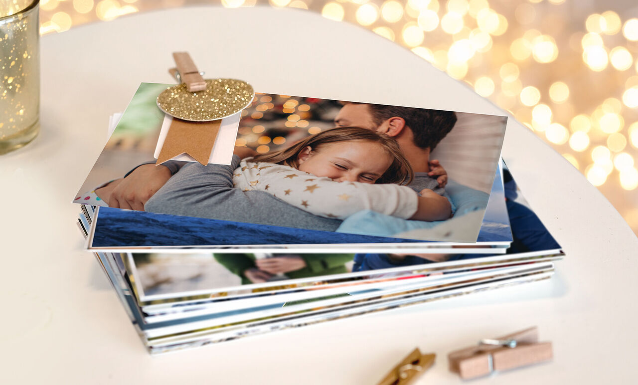 Une maman serre son enfant dans ses bras. Plusieurs photos sont sur une table. Décor scintillant en arrière-plan.