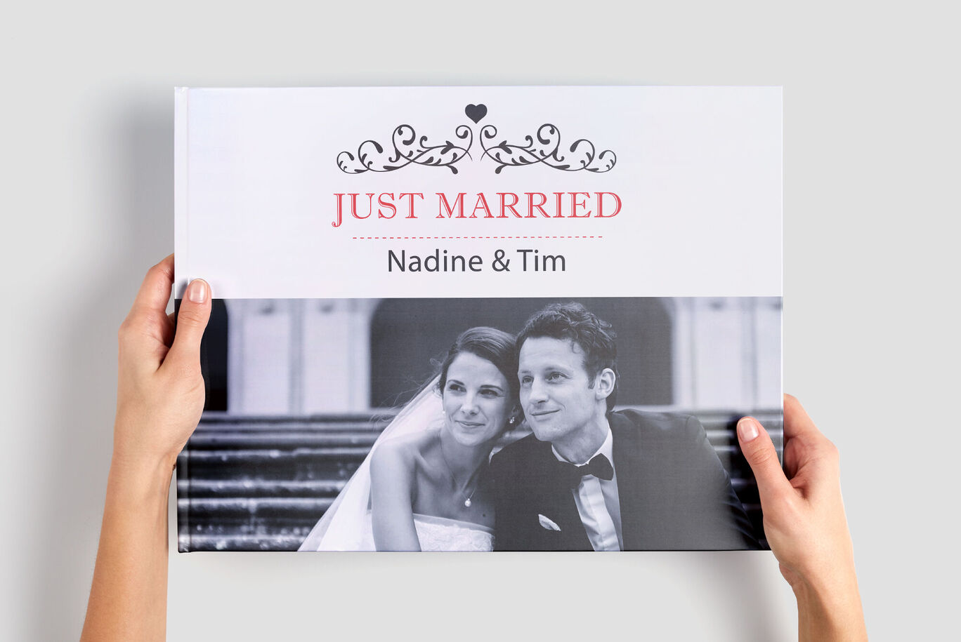 Des mains tiennent un CEWE ALBUM PHOTO avec le titre 'Just Married' et les noms 'Nadine & Tim'