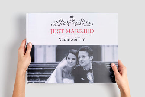 Des mains tiennent un CEWE ALBUM PHOTO avec le titre 'Just Married' et les noms 'Nadine & Tim'