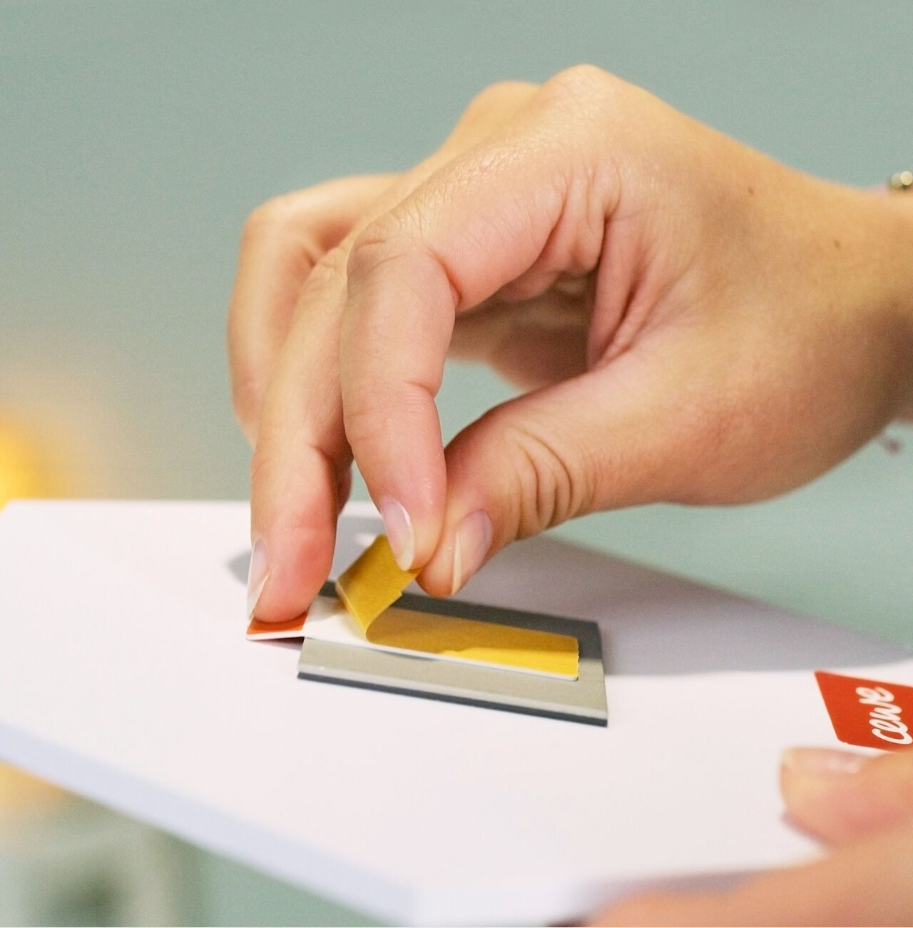 Une main colle un morceau de papier jaune sur une carte de vœux