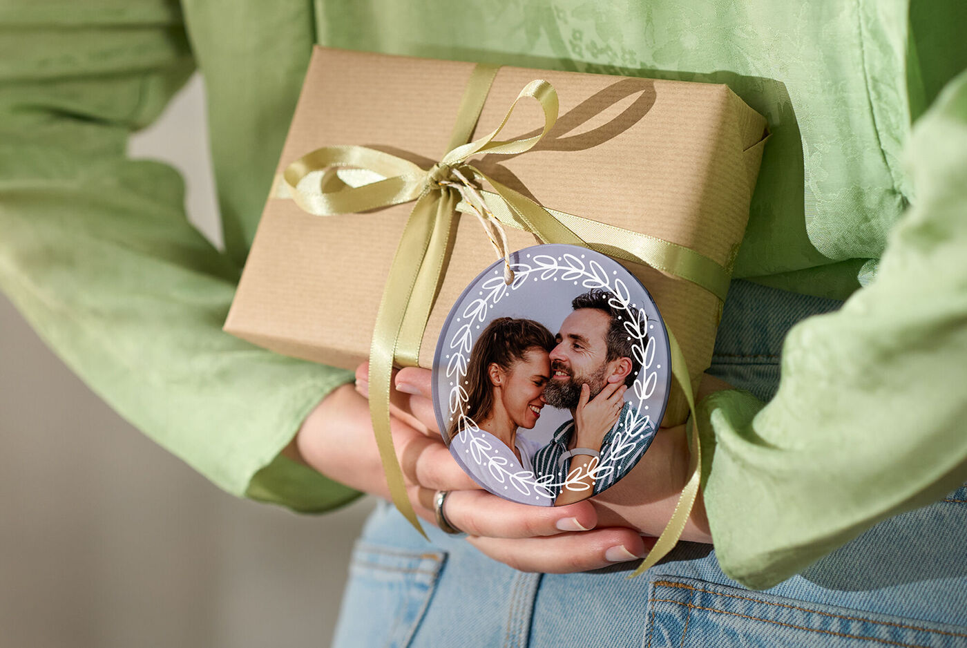Une personne tient un cadeau soigneusement emballé avec un pendentif personnel dans les mains.