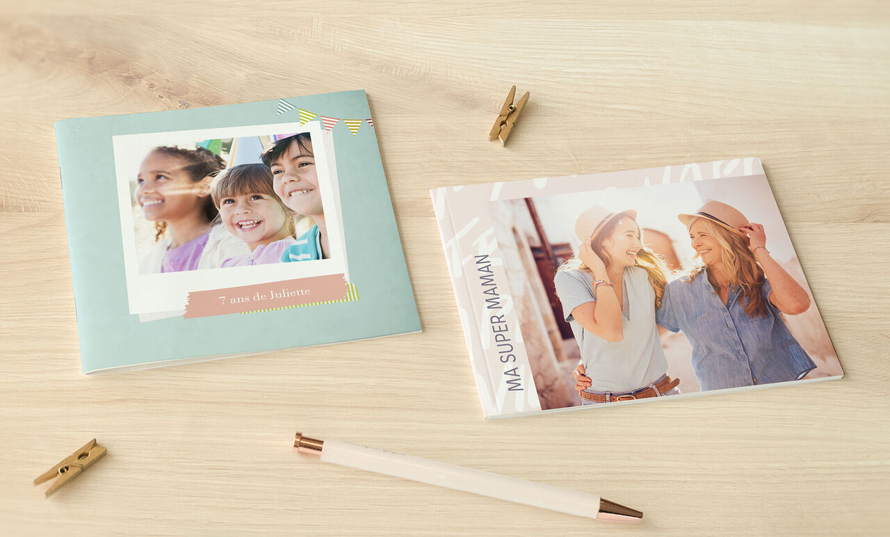 Deux albums photo affectueux sur une table, un en papier et l'autre dans une couverture transparente, idéals pour des souvenirs