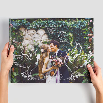 Deux personnes se tiennent dans la nature avec un CEWE PHOTOBOOK floral, diffusant une atmosphère romantique.