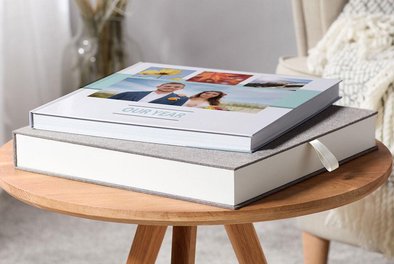 Deux ALBUMS PHOTO CEWE sur une table. Un livre a une couverture avec des photos, l'autre est simple et décoratif.