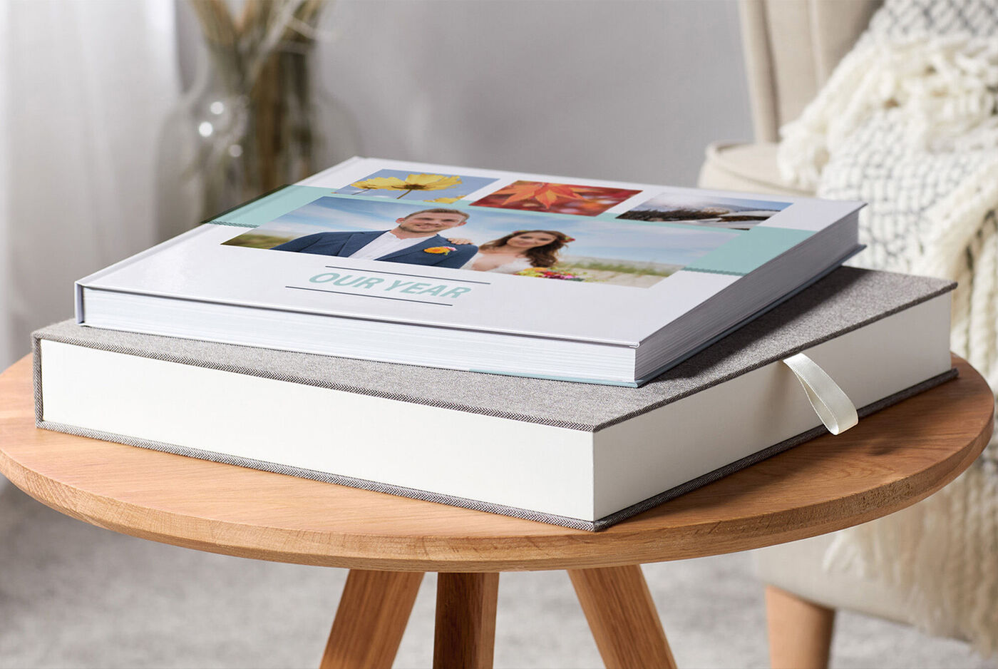 Deux ALBUMS PHOTO CEWE sur une table. Un livre a une couverture avec des photos, l'autre est simple et décoratif.