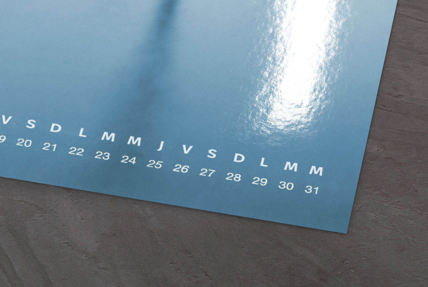 Un calendrier photo CEWE sur une table avec une écriture argentée pour les jours du mois.