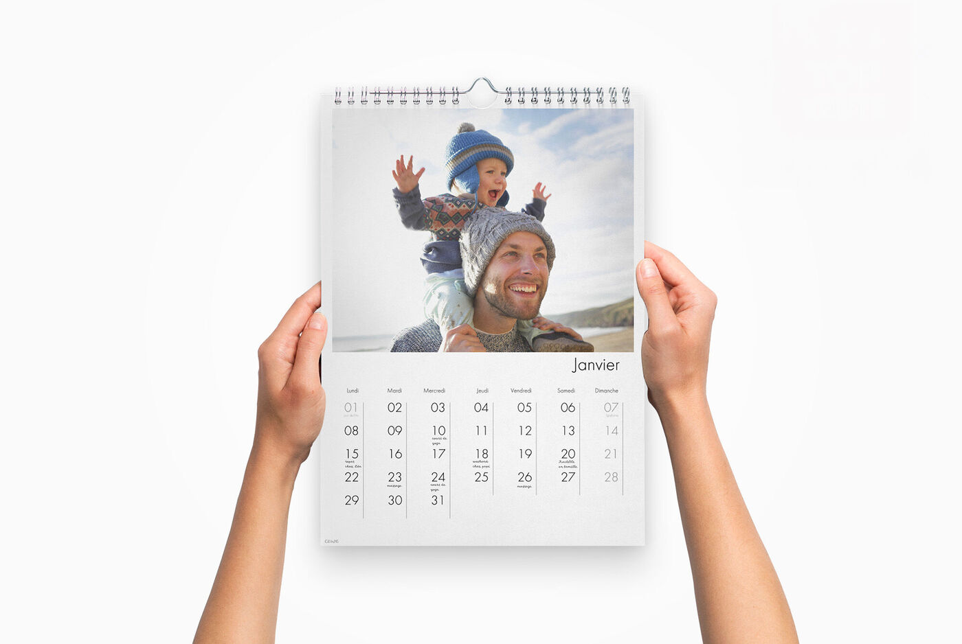 Une main tenant un calendrier de janvier, avec un enfant heureux qui joue.
