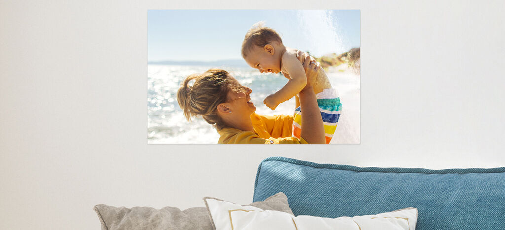 Une mère heureuse soulève son bébé à la plage, tous deux rayonnent de joie.