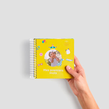 Main colorée tenant un album photo CEWE avec un design estival.