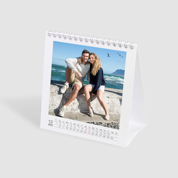 Un magnifique calendrier de table avec un couple assis au bord de la mer. Les vagues créent une belle toile de fond de souvenirs.