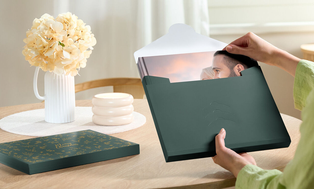 Une personne sort une photo d'une boîte verte sur une table.