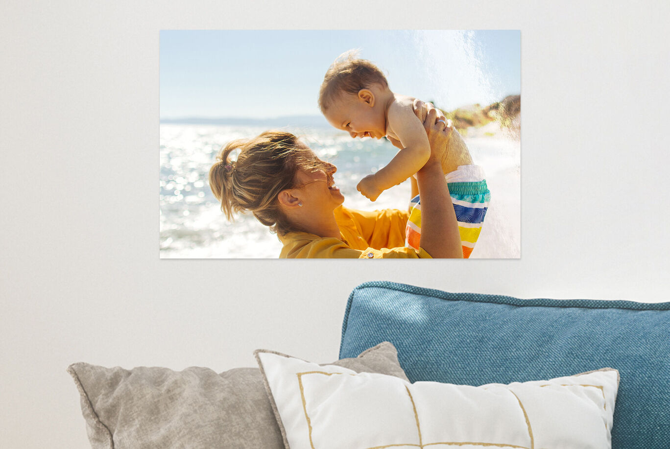 Une personne heureuse soulève un bébé au-dessus de l'eau, tous deux rayonnent de joie.