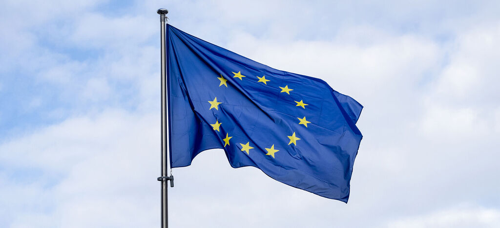 Bannière bleue avec des étoiles jaunes du drapeau UE flottant au vent.