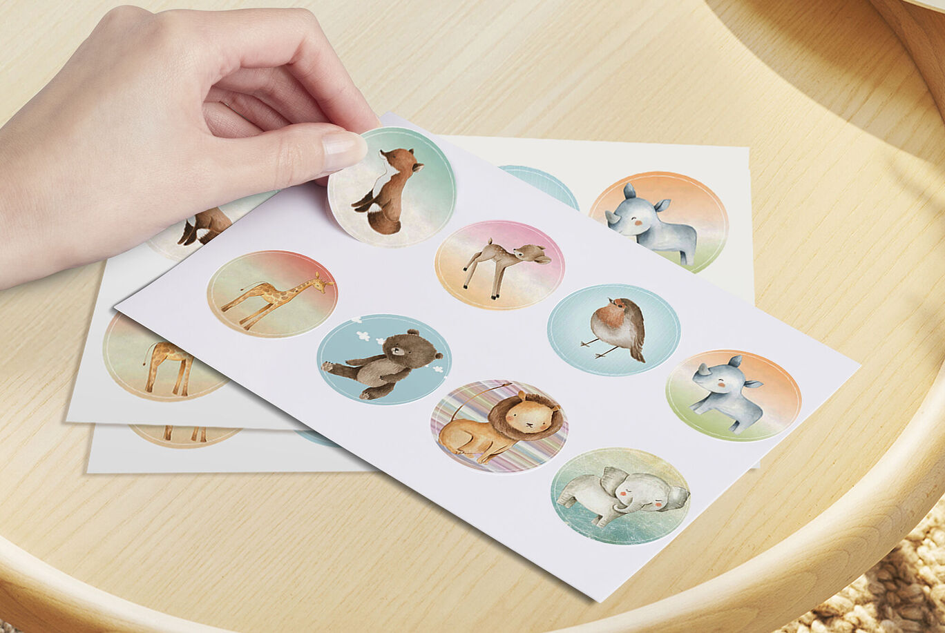Une main tient un autocollant d'un animal mignon sur une feuille avec des animaux colorés et un fond doux.