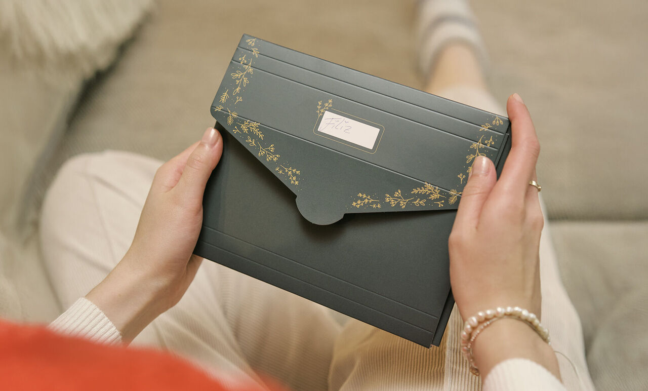 Une personne tient une boîte de cartes CEWE bien emballée et est détendue.