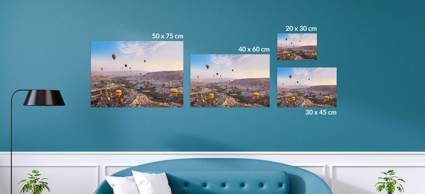 Oeuvres d'art en différentes tailles sur un mur bleu, entourées de meubles.