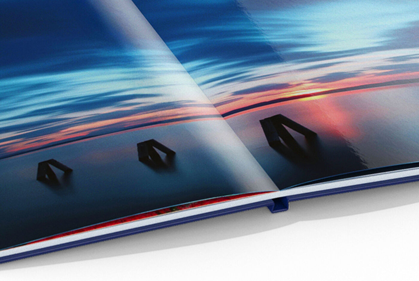 Un livre photo ouvert montrant une belle paysage avec un coucher de soleil lumineux sur l'eau calme.