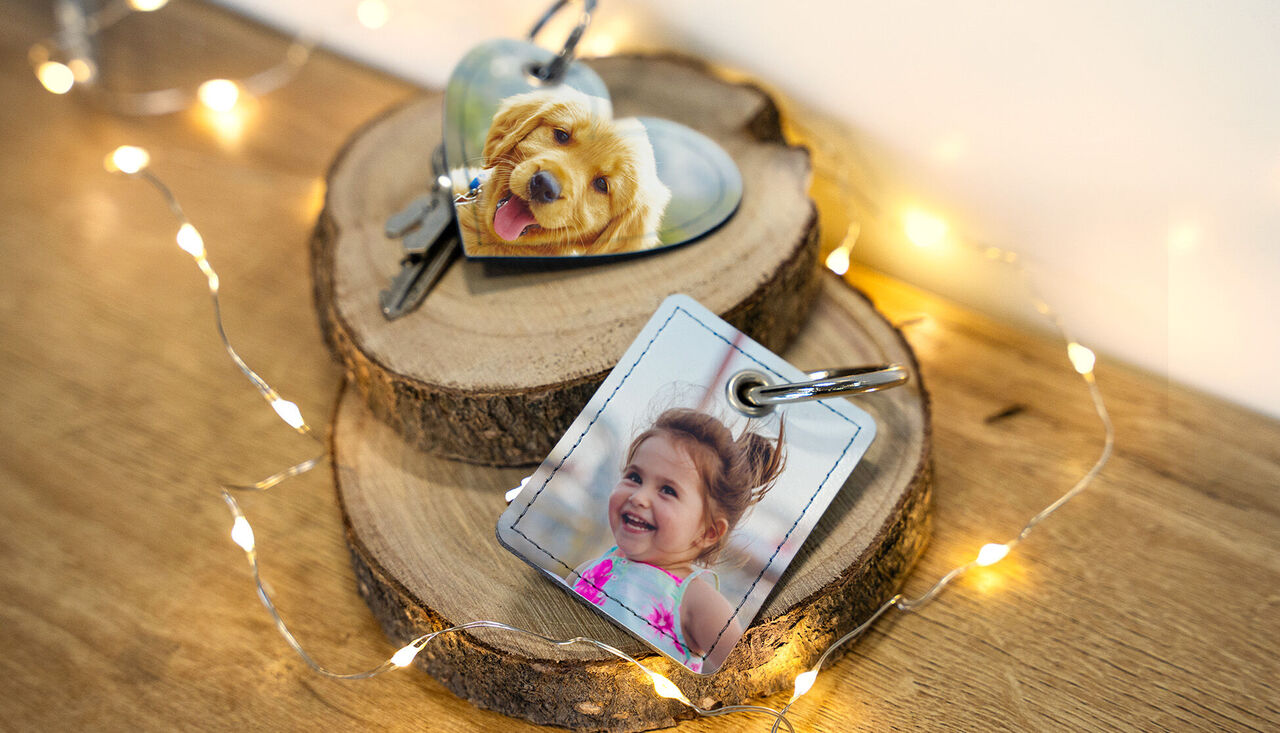 Deux porte-clés personnalisés reposent sur une planche de bois, entourés de lumière chaude.