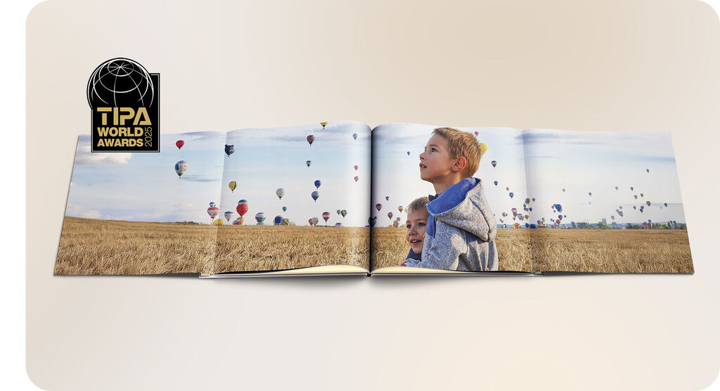 Un livre photo ouvert avec un grand champ et de nombreux ballons dans le ciel.