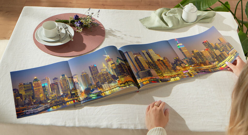 Une personne feuillette un livre photo ouvert avec une vue nocturne de Philadelphie sur une table.