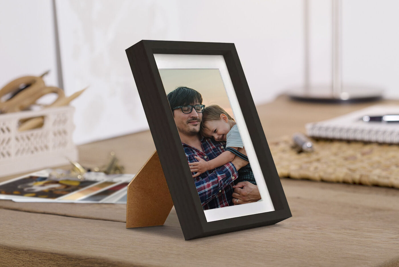 Un magnifique cadre photo avec une photo d'un câlin affectueux. Le cadre est sur une table en bois, entouré d'autres souvenirs.