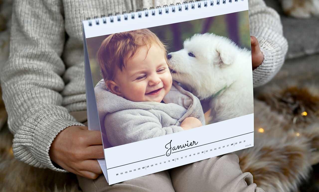 Un enfant avec un chien blanc sur un calendrier de janvier.