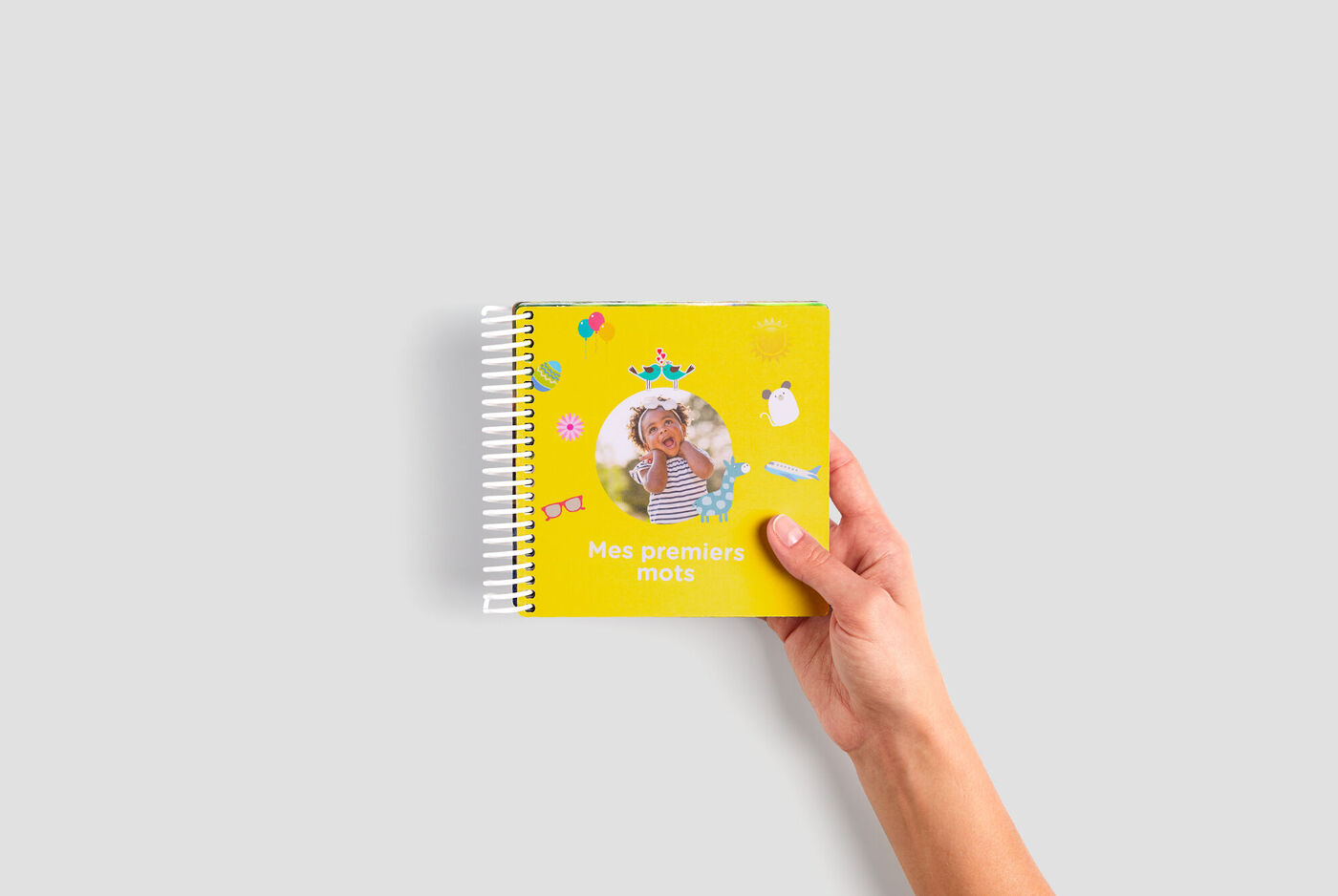 Des mains tenant un livre photo jaune avec un enfant sur la couverture